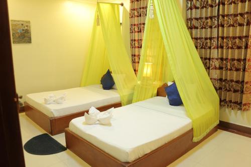 two beds in a room with yellow drapes at Golden Noura Villa-Pub & Restaurant in Phnom Penh