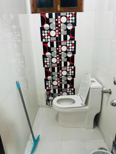 a bathroom with a toilet with a black and white curtain at BuddhaInn-An Enchanted Villa in Varanasi