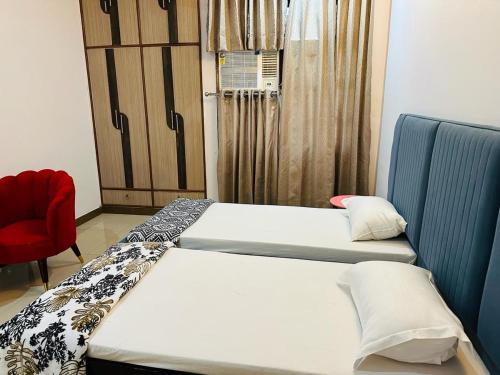 a room with two beds and a red chair at BuddhaInn-An Enchanted Villa in Varanasi