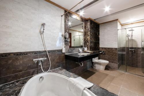 a bathroom with a tub and a sink and a toilet at A25 Hotel - 44 Hàng Bún in Hanoi