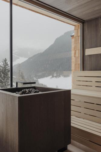 a room with a bath tub with a large window at Hotel Marten - Ski-In & Ski-Out in Saalbach Hinterglemm