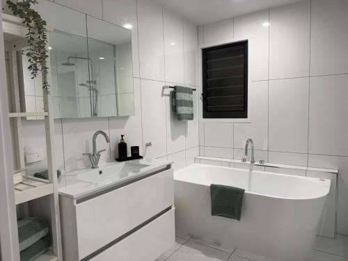 a white bathroom with a tub and a sink at SeaSide Serenity - beach 200m in Mudjimba