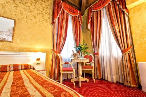 a bedroom with a bed and a table and curtains at Ca' San Polo - Ferretti Hotels Collection in Venice