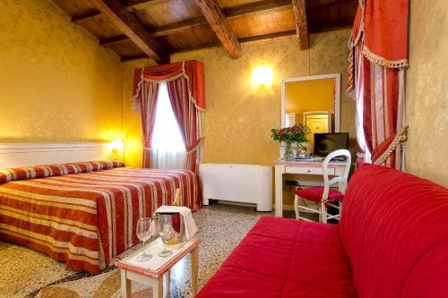 a hotel room with a bed and a couch and a mirror at Ca' San Polo - Ferretti Hotels Collection in Venice
