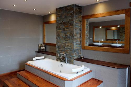 a bath tub in a bathroom with two sinks and a mirror at Maison d hôtes "Aux Légendes d Ardenne" in Carlsbourg