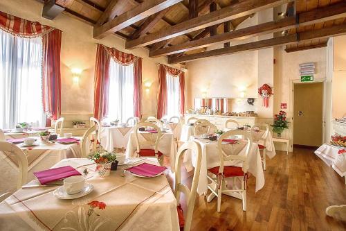 un restaurante con mesas y sillas blancas y ventanas en Ca' San Polo, en Venecia