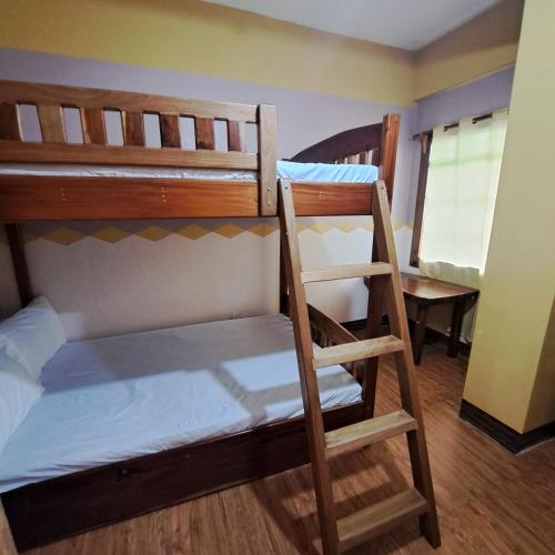 two bunk beds in a room with a ladder at Baguio Tourist Cabin in Baguio