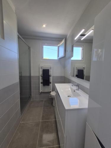 a white bathroom with a sink and a shower at Lake Villa Castéra-Verduzan in Castéra-Verduzan