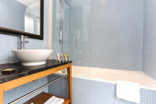 a blue tiled bathroom with a sink and a tub at Avalon Hotel in Paris