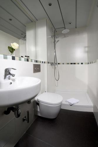 une salle de bain blanche avec un lavabo et des toilettes dans l'établissement Hôtel Orchidée, à Paris