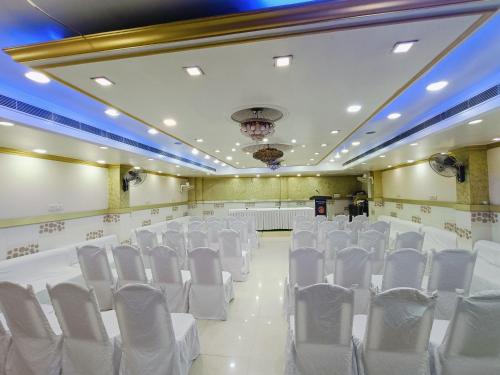 a room with rows of white chairs in a hall at Saluja Palace in Rāe Bareli