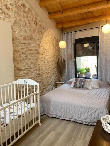 a bedroom with a crib and a stone wall at AltHouse Canet lo Roig in Canet lo Roig