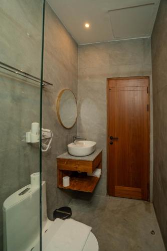 a bathroom with a sink and a toilet and a mirror at Arca Jungle View Luxury Villa Ubud in Ubud