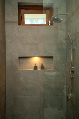 a bathroom with a shower with a glass door at Arca Jungle View Luxury Villa Ubud in Ubud