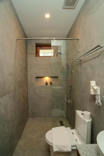a bathroom with a glass shower and a toilet at Arca Jungle View Luxury Villa Ubud in Ubud