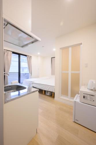 a white room with a bed and a kitchen at Oku Apartment in Tokyo