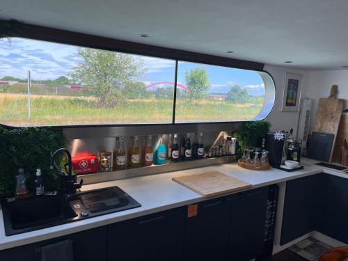 a kitchen with a counter and a window with bottles at Péniche Bonne Chance in Eckwersheim