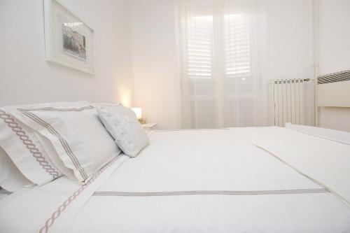 een witte slaapkamer met een wit bed en een raam bij Prokonzul 2BR apartment in old town in Zadar