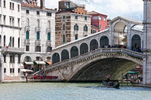 a bridge over a river with a gondola in the water at Ca' San Polo - Ferretti Hotels Collection in Venice