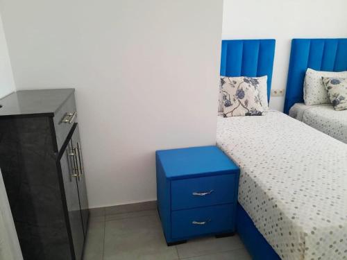 a small bedroom with a blue bed and a dresser at Appartement complexe Costa Mar avec piscine privée très sécurisé 3min de la plage Luxe et détente in Martil
