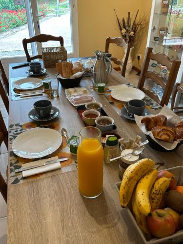 een tafel met ontbijtproducten en een glas sinaasappelsap bij Chalet Chêne-Pin in Boutenac