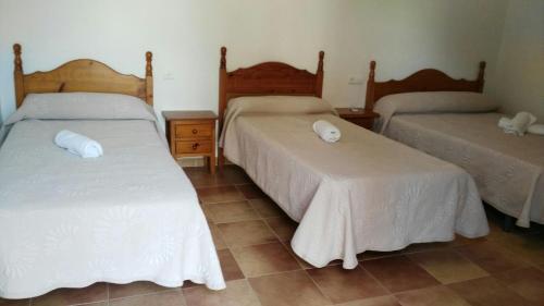 a bedroom with two beds with white sheets at Hostal las Parcelas in Conil de la Frontera