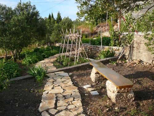 a bench in a garden with a stone path at Murter Inn in Murter