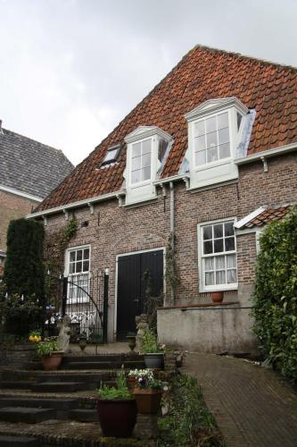 a brick house with white windows and stairs at 't Koetshuys in Heenvliet