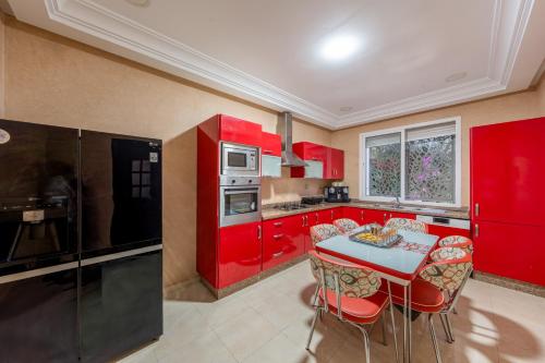 a kitchen with red cabinets and a blue table at Villa 33 haut standing Avec piscine et Hammam in Tangier