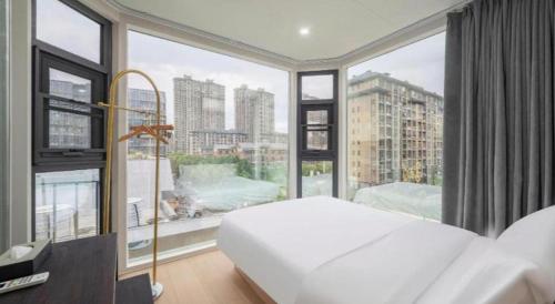 a bedroom with a white bed and a large window at Lavande Hotels Xuzhou Yunlong Wanda Medical University in Xuzhou