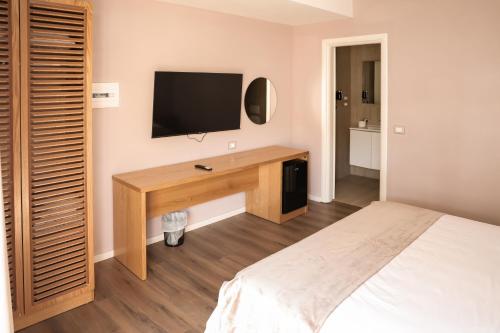 a bedroom with a desk with a television on the wall at Hotel Platinium Dhermi in Vlorë