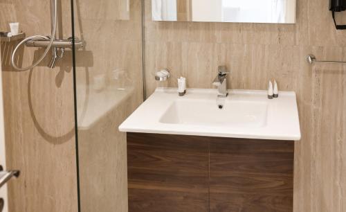 a bathroom with a white sink and a shower at Hotel Platinium Dhermi in Vlorë