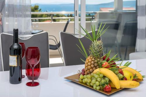 a plate of fruit on a table with a bottle of wine at Apartments ŽAJA in Seget Vranjica