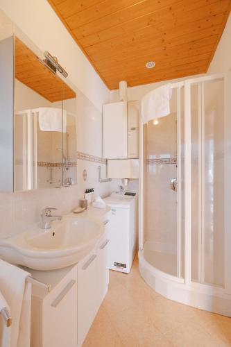 a white bathroom with a sink and a shower at Goldengel Ferienwohnung im Herzen Kalterns mit einer Terasse zum verlieben in Caldaro