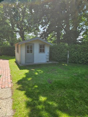 a small house in a grassy yard with trees at Ferienhaus mit großem Garten in Friedeburg