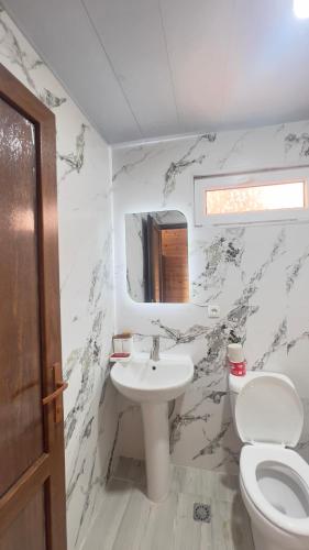 a white bathroom with a toilet and a sink at Luna di Mare in Ureki
