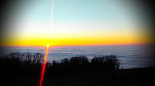 a sunset over the ocean with a light pole at Riegrova Chata Kozákov in Semily