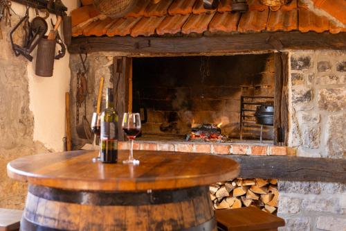 a table with a glass of wine in front of a fireplace at Old house Rustica with pool, jacuzzi and tavern - Valincic in Brinje