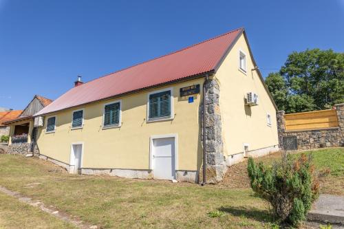 an old yellow building with a red roof at Old house Rustica with pool, jacuzzi and tavern - Valincic in Brinje