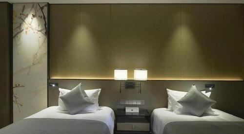 a hotel room with two beds with white pillows at Golden Eagle Summit Hotel Kunshan in Suzhou