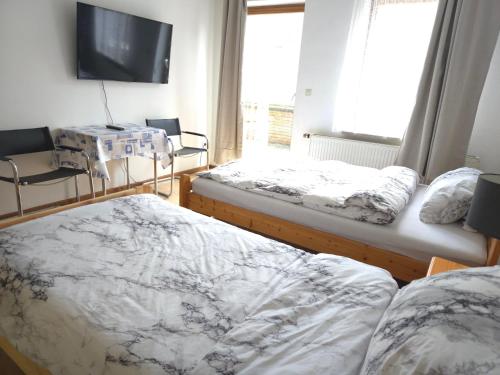 a bedroom with two beds and a tv on the wall at Unterkunft für Monteure in Schwallungen