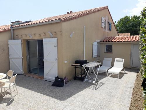 un patio avec des chaises et une table et un bâtiment dans l'établissement Maison entièrement restaurée et meublée à neuf, à Saint Cyprien Plage