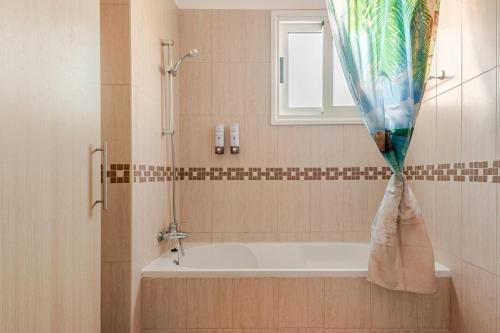 TersephanouにあるMajestic Sea View Apartmentのバスルーム(バスタブ、窓、シャワーカーテン付)が備わります。