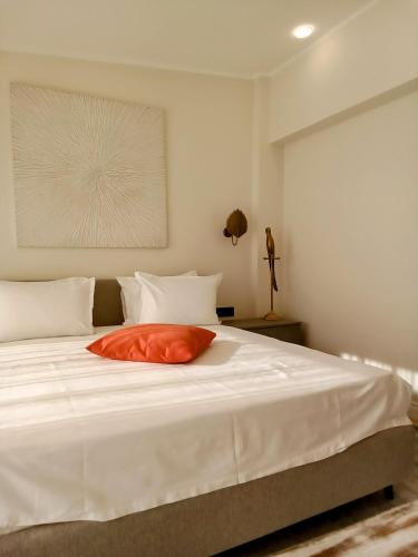 a large white bed with a orange pillow on it at Dimitris Residence in Tivat
