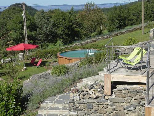 a swimming pool with two lawn chairs and a red umbrella at le Henry in Queyrières