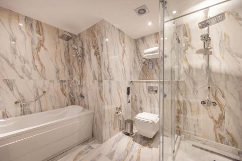 a bathroom with a shower and a toilet and a sink at Helnan Antoniades Palace Hotel in Alexandria