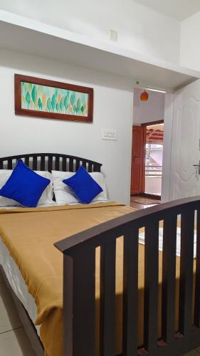 a bedroom with a large bed with blue pillows at Ashirvad Homes in Mannārakkāt