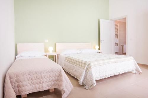 een witte slaapkamer met 2 bedden en een spiegel bij Nonna Nina in Guagnano