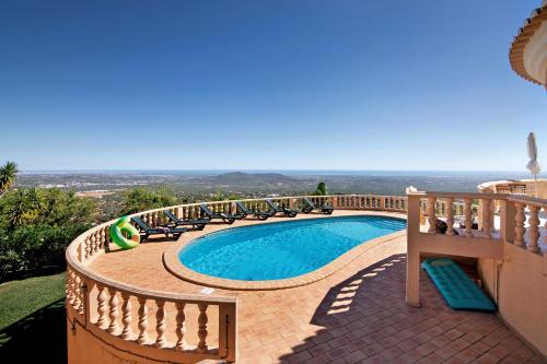 a swimming pool with chairs and a view of the ocean at Quinta da Violeta in Loulé