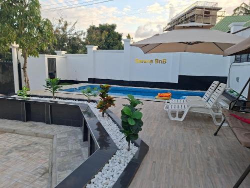a patio with an umbrella and a swimming pool at Serene BnB - Apt 01 Makongo after Mlimani City in Dar es Salaam